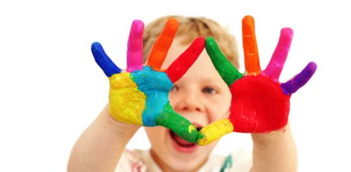 Five year old boy with hands painted in colorful paints ready for hand prints